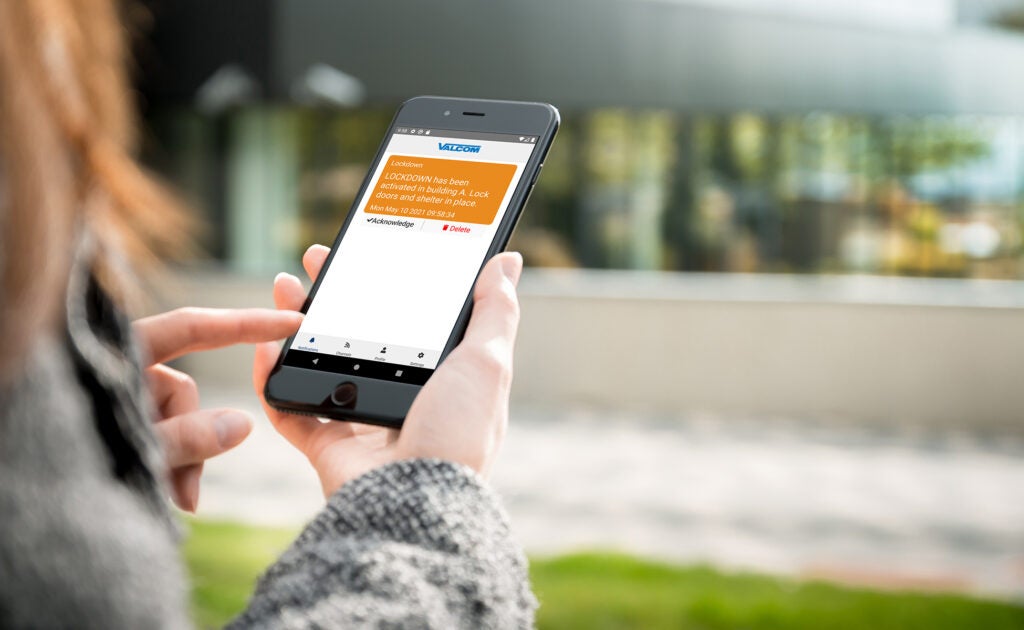 Lady holding a mobile phone with V-Alert Lockdown notification